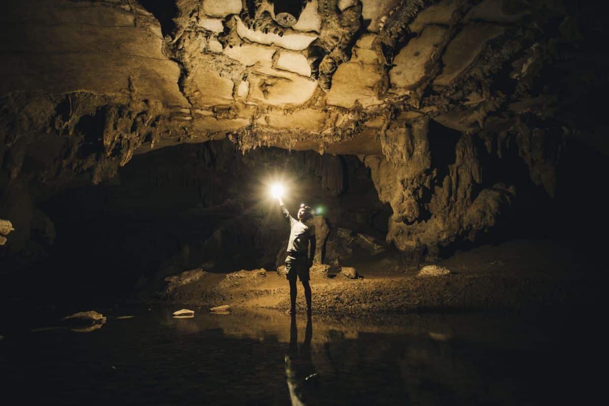 A man with a light flash exploring a big cave.