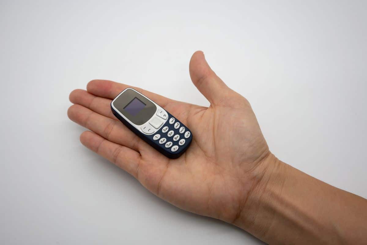 A tiny cell phone in the palm of the hand.
