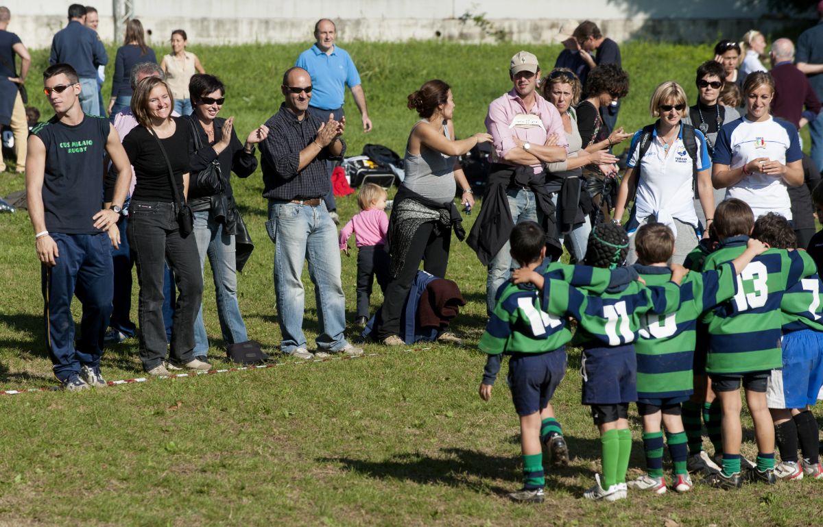 Parents cheering their kids at football match.
