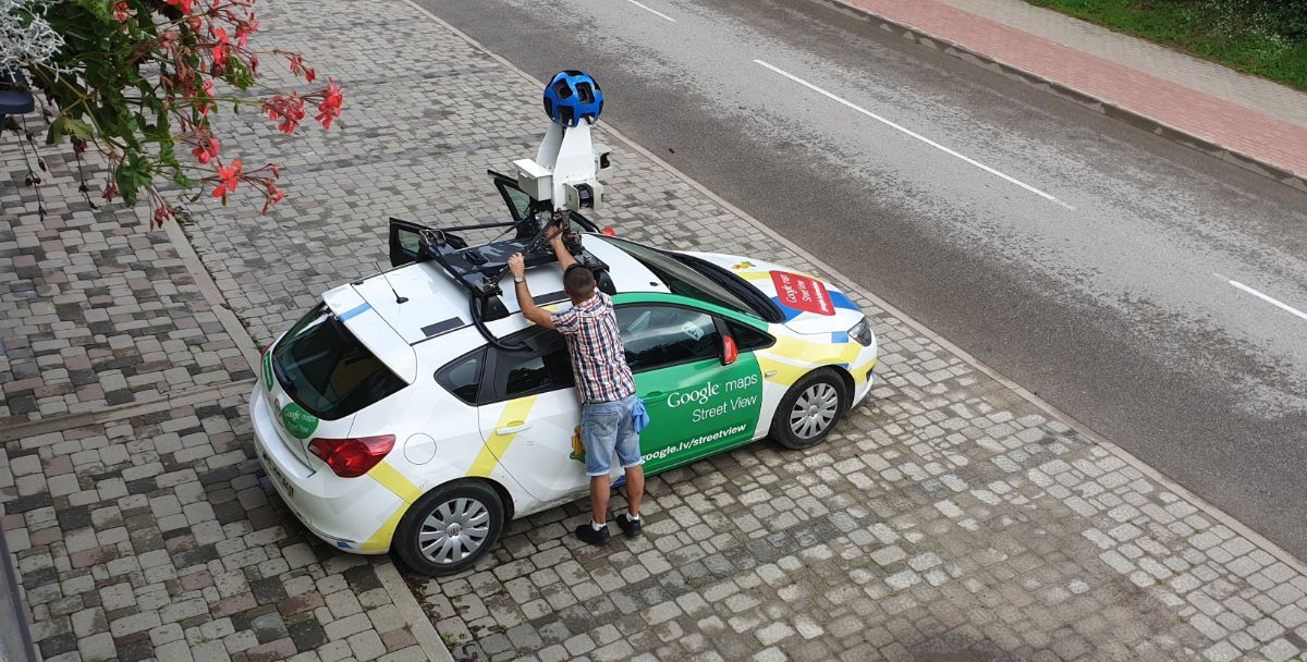 A man fixes a camera system on a google street view car.