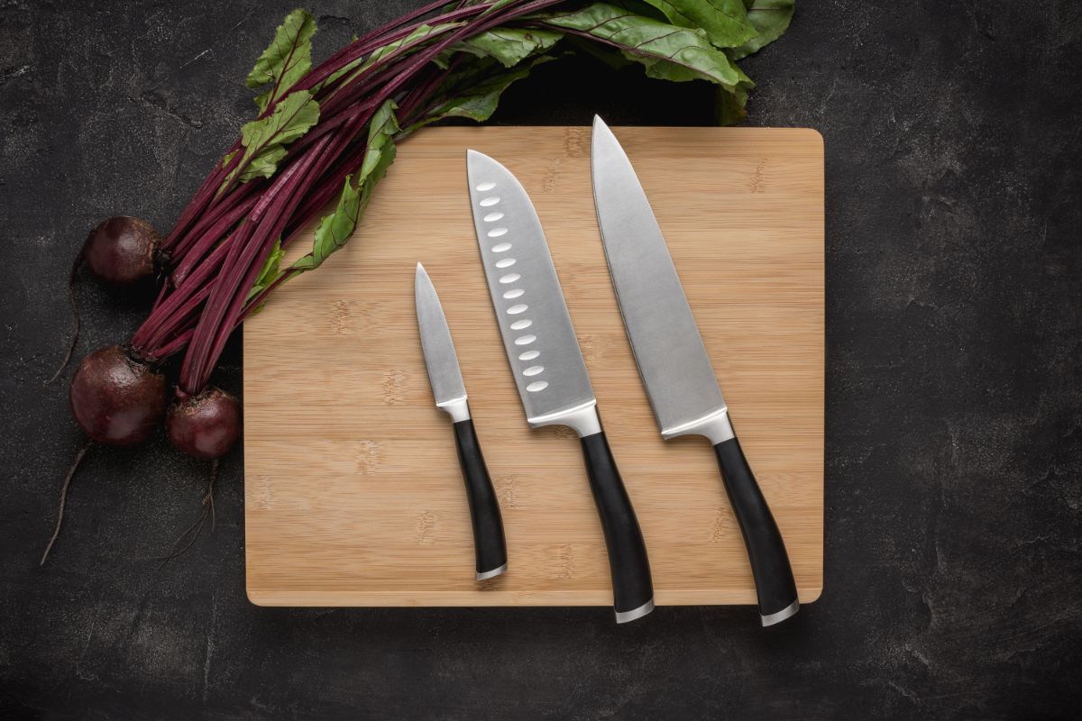 Three kitchen knives on a wooden cutting board.
