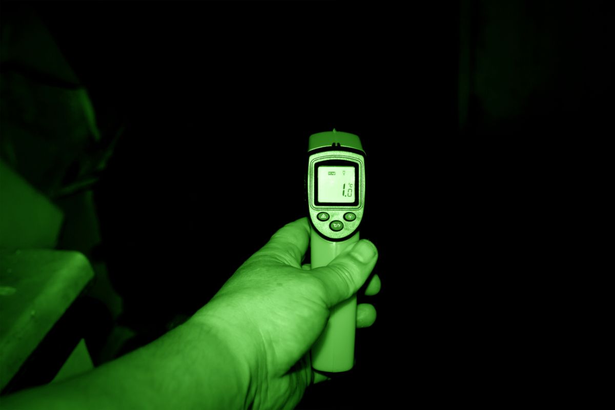 A man using a digital thermometer during the night.