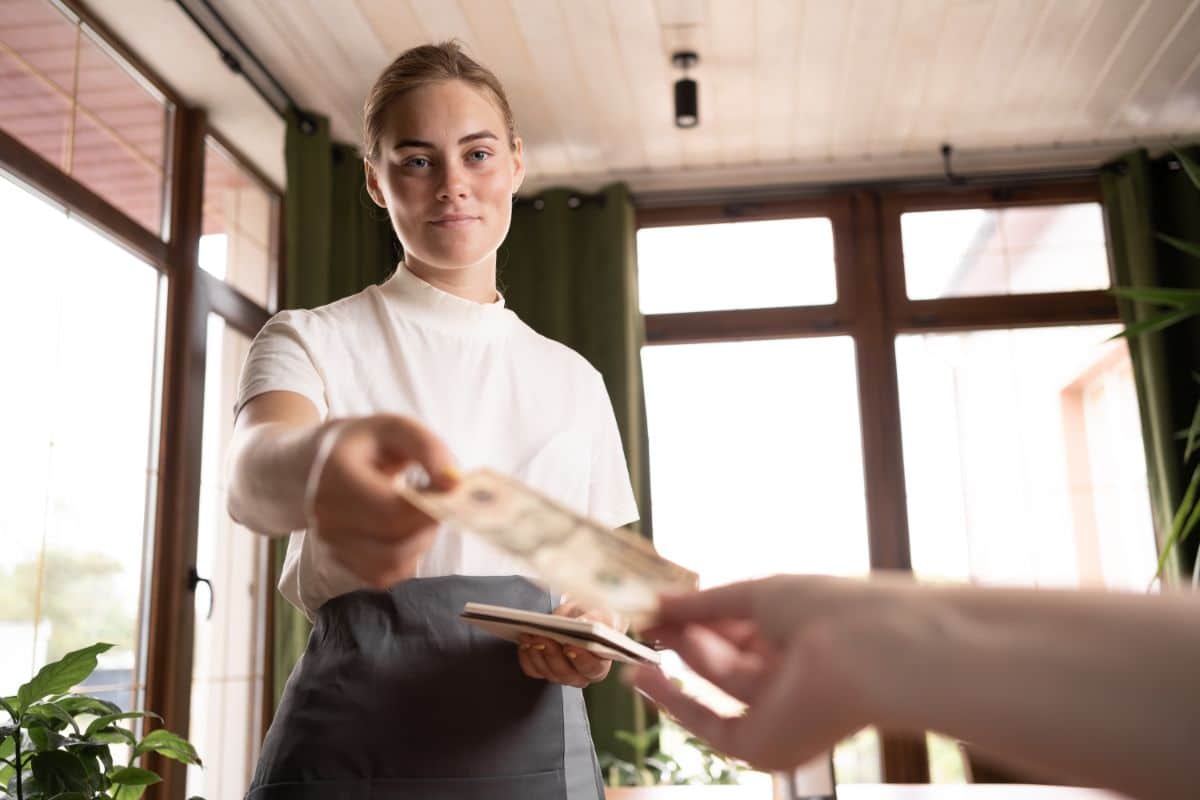 A young waitress taking a tip.