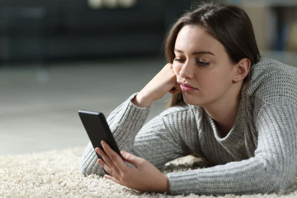 A bored young woman looking at her phone.