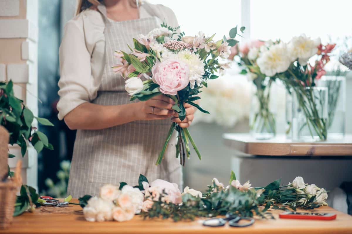 A florist woman prepares a bouquet in a flower shop.