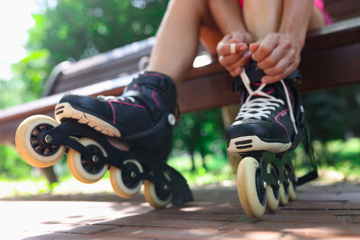 A woman is putting on her roller skaters.