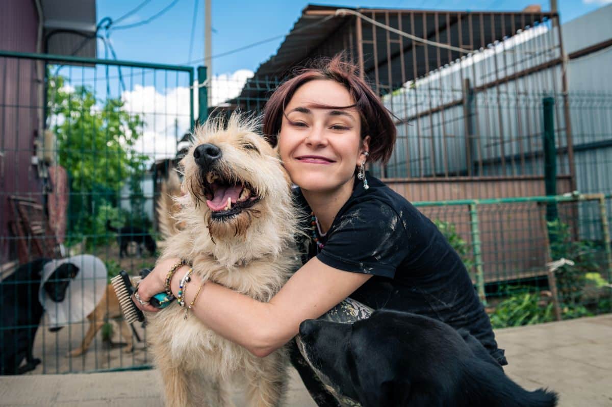 A young woman is hugging a dog.