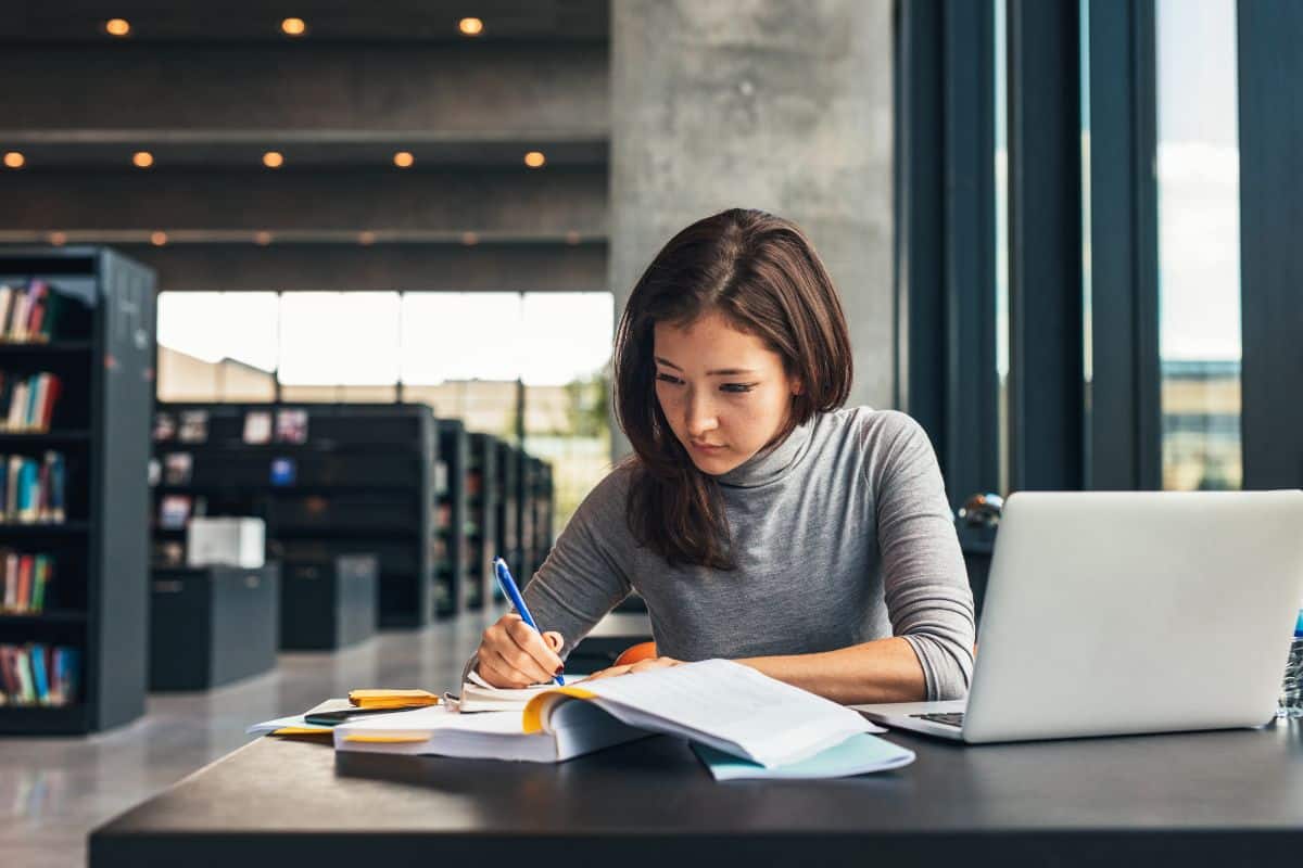 A young female college student studying  in a library.