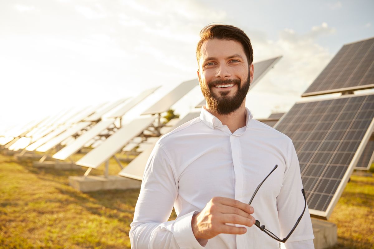 A young, positive man near solar panels.