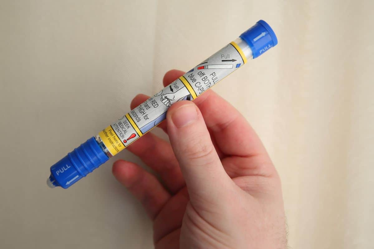 A hand holds an EpiPen.