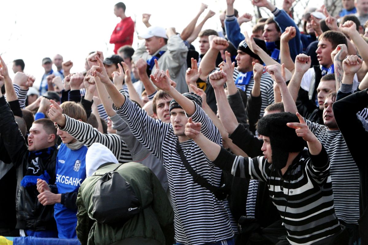 A bunch of young men cheering and rooting on a football match.