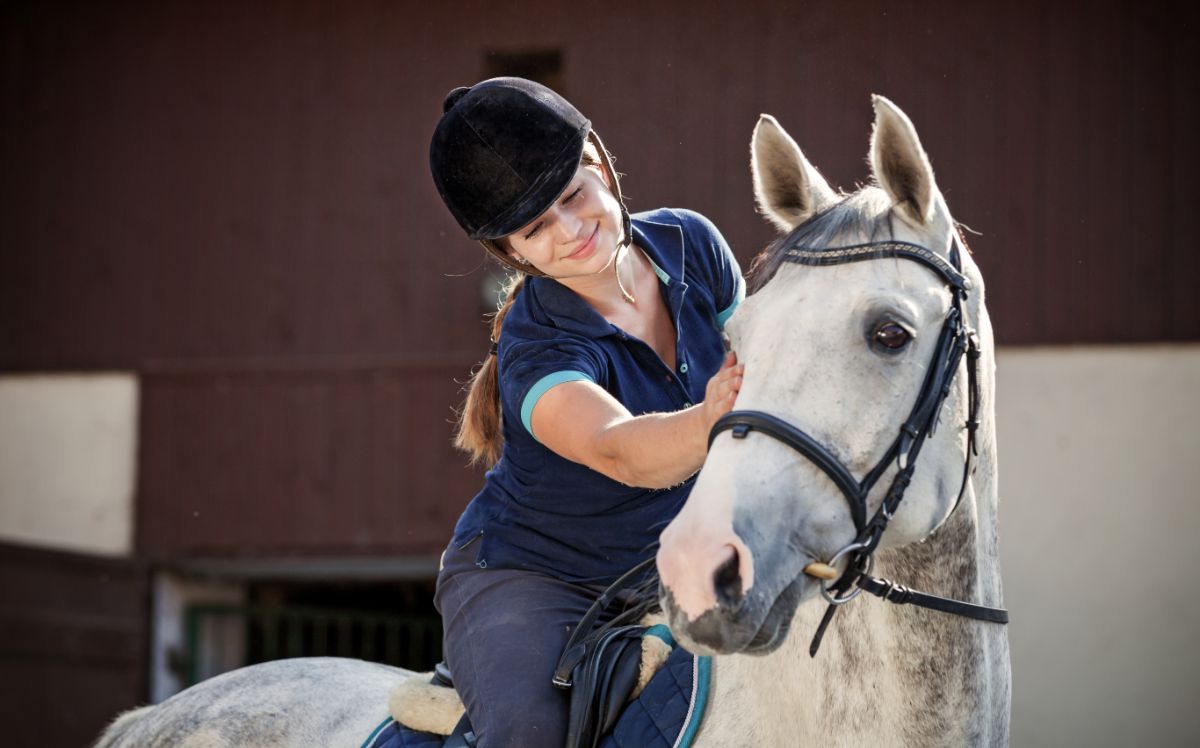 A woman petting her white horse.