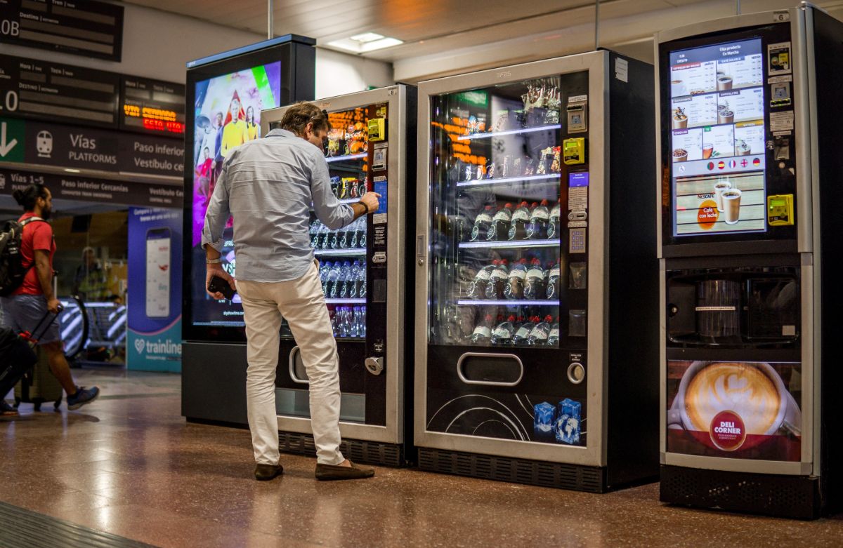 A man is using a vending machine at a mall.