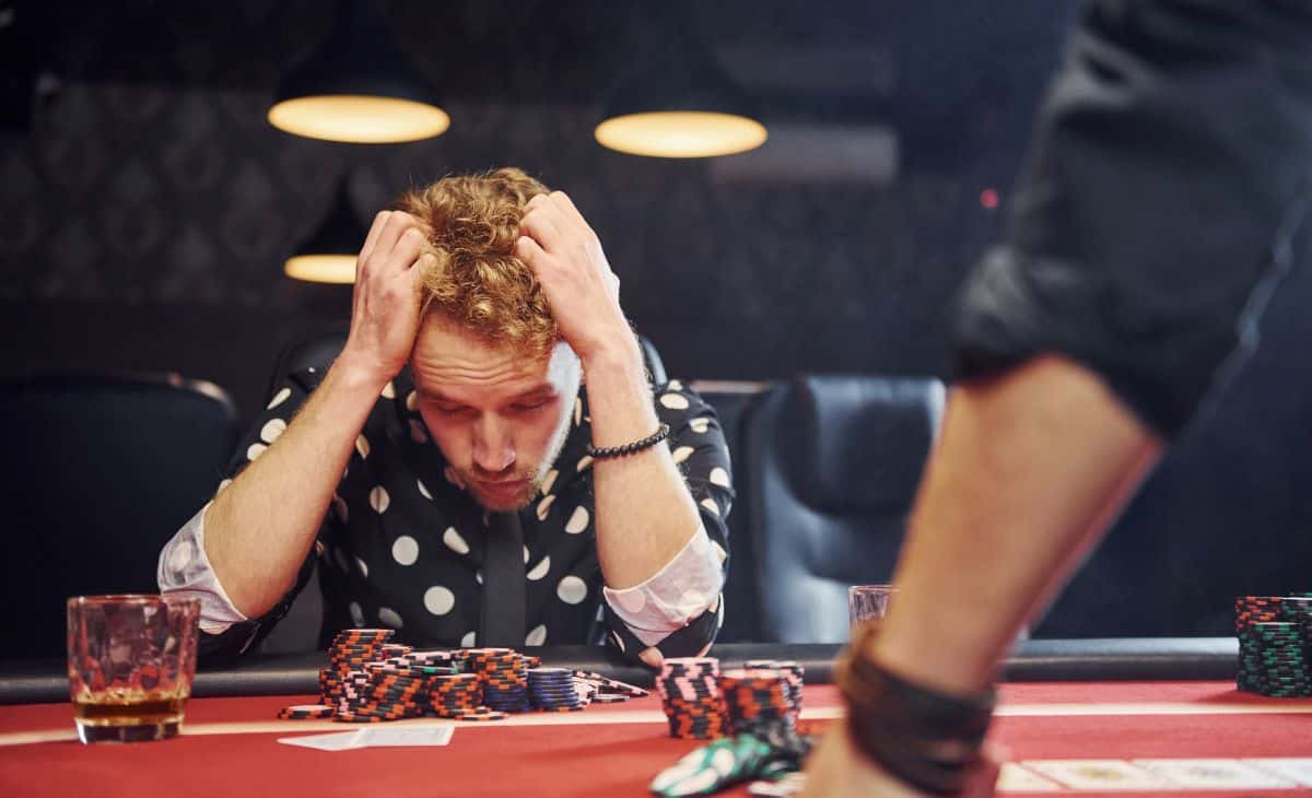 A sad man losing a poker game in a casino.